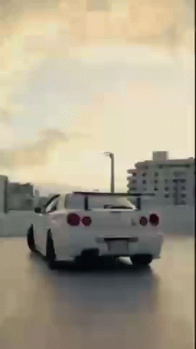 White Car Driving in Parking Lot With City Background