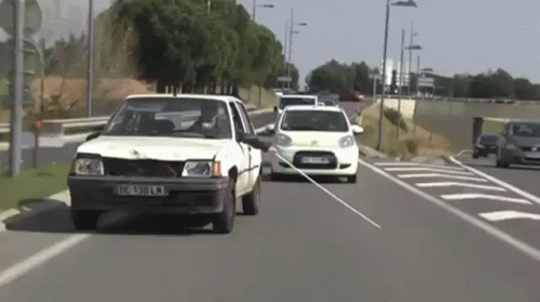 White Car With License Plate IC 389 KM Driving Down Street