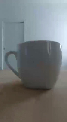 White Coffee Cup on Wooden Table in Front of Door