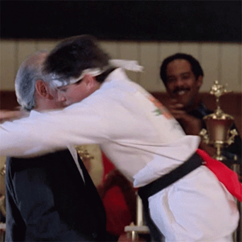 White Karate Uniform Man Hugging Black Suit Man GIF