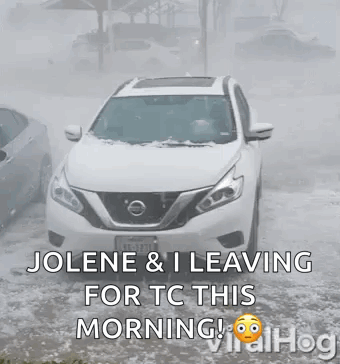 White Nissan SUV Driving Through Snowy Street
