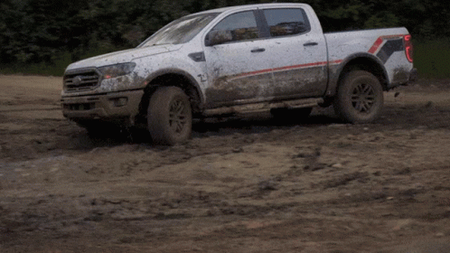 White Pickup Truck Driving Through Muddy Field