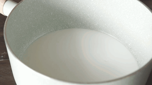 White Pot With Wooden Handle Filled With Milk
