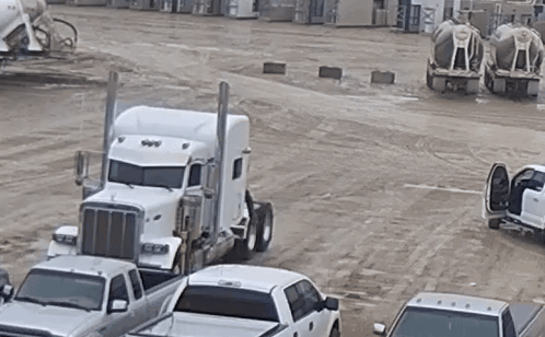 White Semi Truck Parked Next to Row of White Trucks