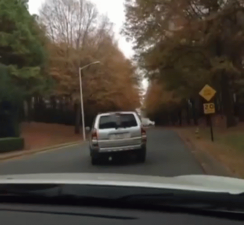 White SUV Driving Down Road With 20 Sign