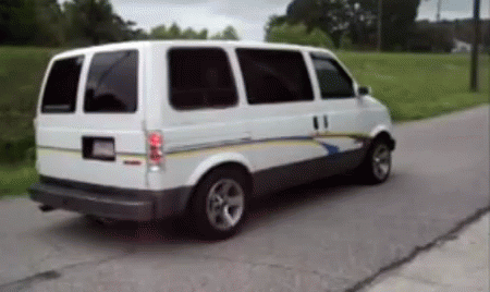 White Van Driving Down Road With Trees