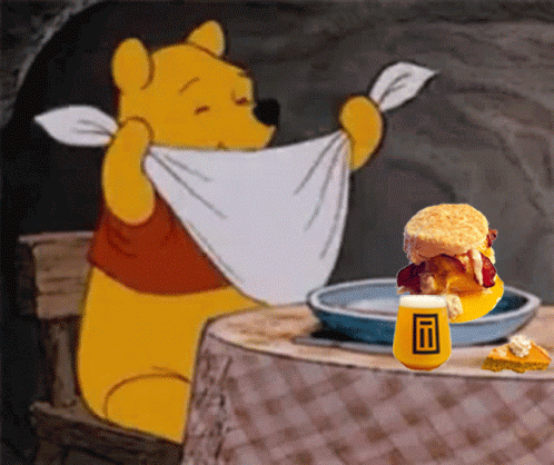 Winnie The Pooh Is Sitting At A Table With A Plate Of Food GIF
