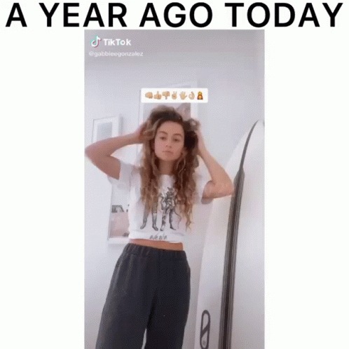 Woman Adjusting Hair Next to Surfboard A Year Ago Today