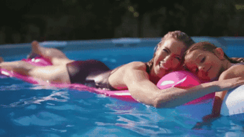 Woman and Child Laying on Rafts in Pool