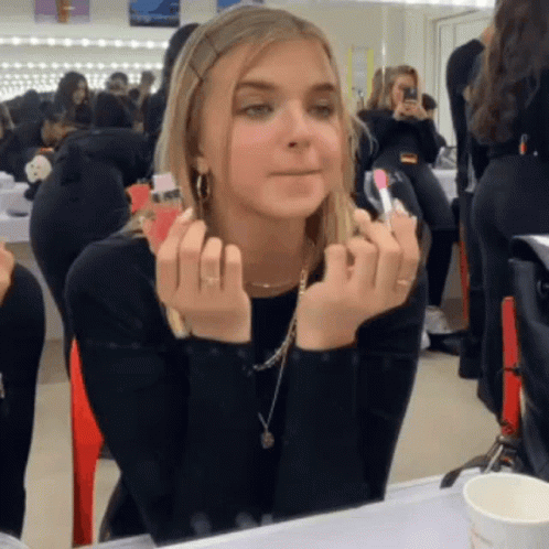 Woman Applying Lipstick in Front of Mirror