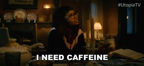 Woman at Table With Coffee Saying I Need Caffeine