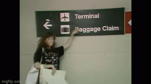 Woman at Terminal Baggage Claim Sign