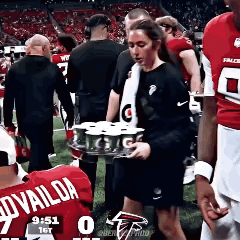 Woman Carrying Tray Of Cans On Football Field GIF