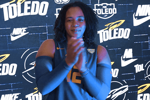 Woman Clapping in Front of Toledo Wall