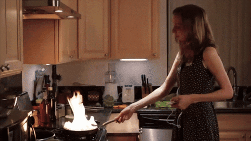 Woman Cooking on Stove With Flames From Pan