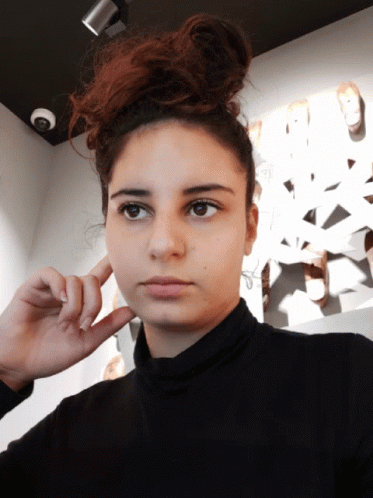 Woman Covering Ear In Black Turtleneck GIF