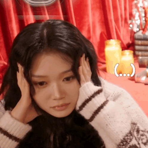 Woman Covering Ears in Front of Candles