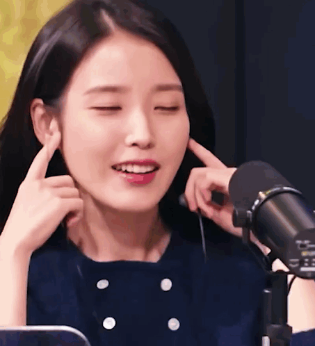 Woman Covering Ears with Eyes Closed at Microphone