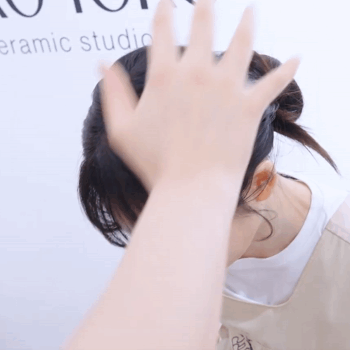 Woman Covering Face Beside Ceramic Studio Sign