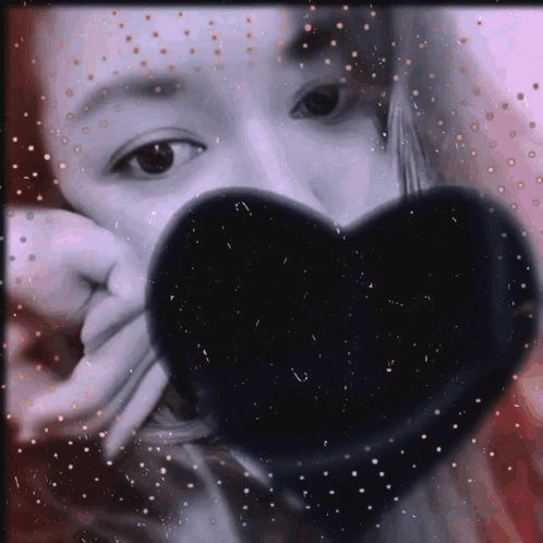 Woman Covering Face With Black Heart-Shaped Object