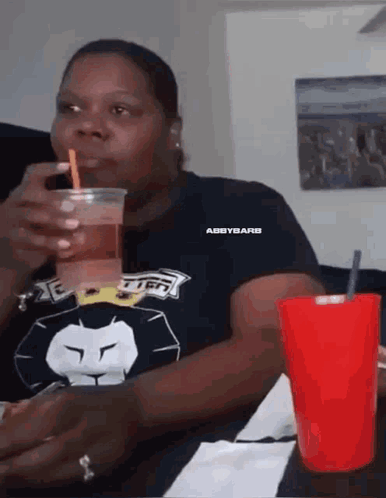 Woman Drinking From Plastic Cup With Straw Sitting At Table