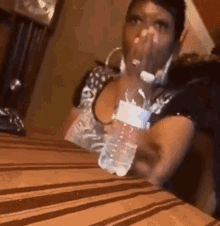 Woman Drinking Water From Plastic Bottle At Table GIF