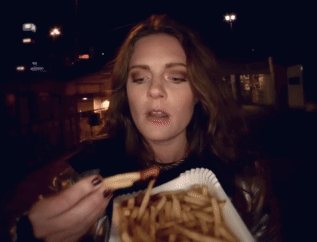 Woman Eating French Fries at Night with Open Mouth