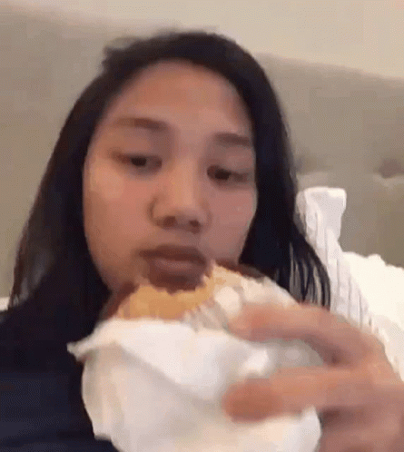 Woman Eating Hamburger on Bed