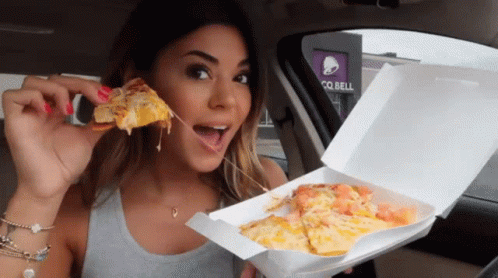 Woman Eating Pizza in Car by Taco Bell Sign