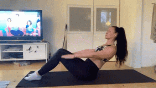 Woman Exercising on Yoga Mat in Front of TV