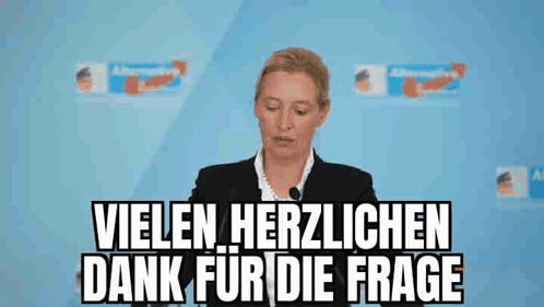 Woman Giving Speech in Front of Vielen Herzlichen Dank For Die Frage Sign
