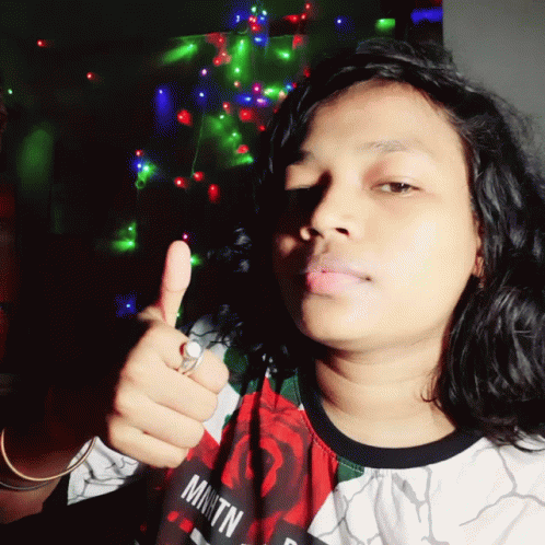 Woman Giving Thumbs Up in Front of Christmas Tree