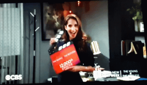 Woman Holding 12,000th Episode Clapper Board