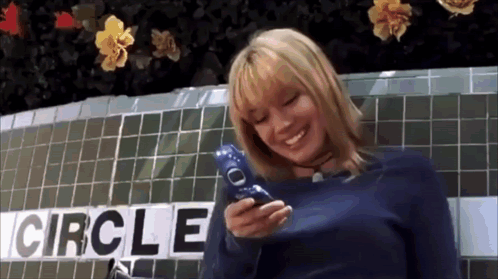 Woman Holding Cell Phone Before Circle Sign