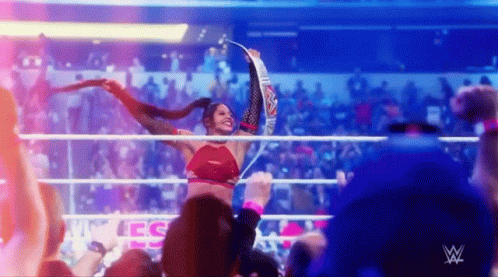 Woman Holding Championship Belt in Wrestling Ring With Crowd