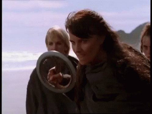 Woman Holding Frisbee Pointing On Beach GIF
