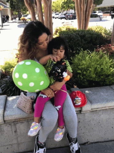 Woman Holding Little Girl and Green Polka Dot Balloon