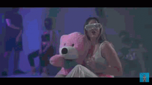 Woman Holding Pink Teddy Bear in Front of Crowd