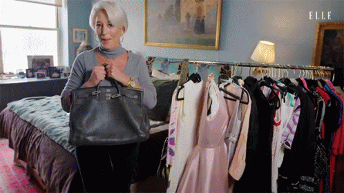 Woman Holding Purse in Front of Clothes Rack