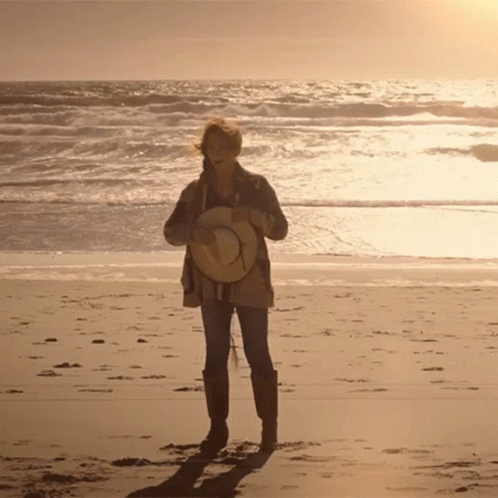 Woman Holding Straw Hat on Beach