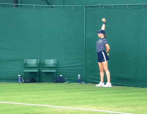 Woman Holding Tennis Ball Over Head on Court