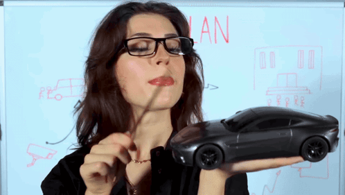 Woman Holding Toy Car in Front of Whiteboard Saying Plan