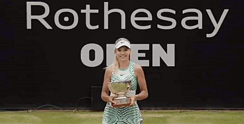 Woman Holding Trophy in Front of Rothesay Open Banner