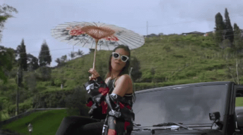 Woman Holding Umbrella Sitting On Car Back GIF
