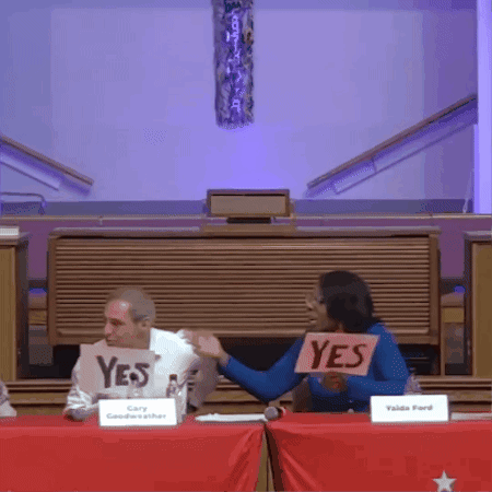 Woman Holding Yes Sign in Front of Man