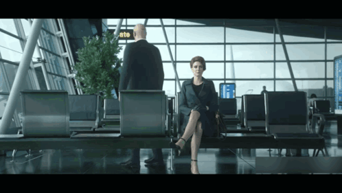 Woman in Airport Waiting Area With Man and Gate Sign
