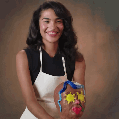 Woman In Apron Smiling Holding Face Sculpture GIF