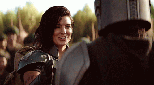 Woman in Armor Smiling at Man in Helmet