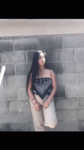Woman In Bandana Top In Front Of Brick Wall GIF