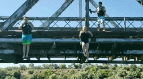 Woman in Bathing Suit Hanging From Bridge